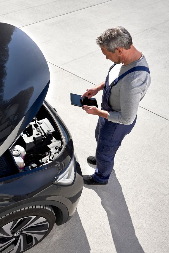 Volkswagen Service Techniker vor geöffneter Motorhaube